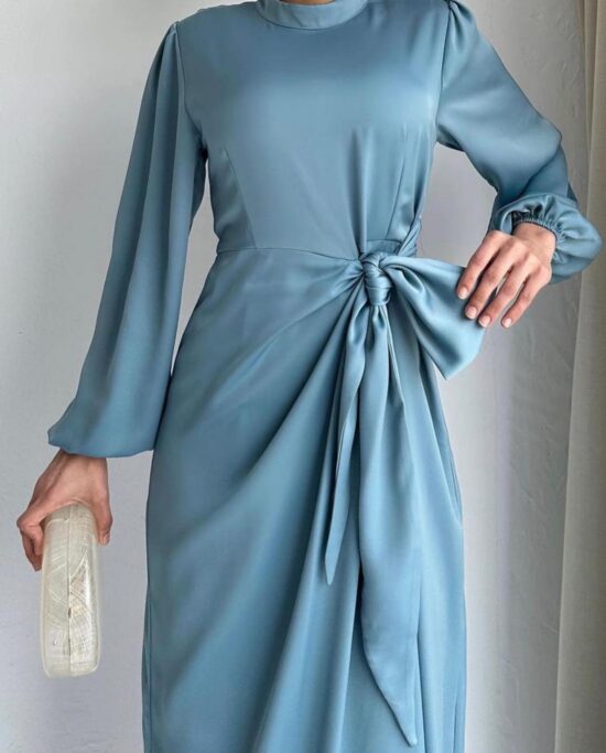 A woman wearing a blue dress with long sleeves and heels.