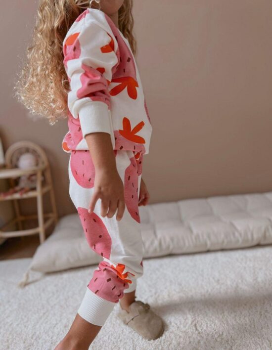 A little girl wearing a Strawberry Tracking suite hoodie and joggers.