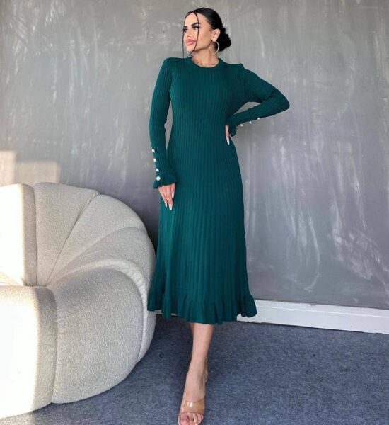 A woman wearing a green dress with long sleeves and heels.