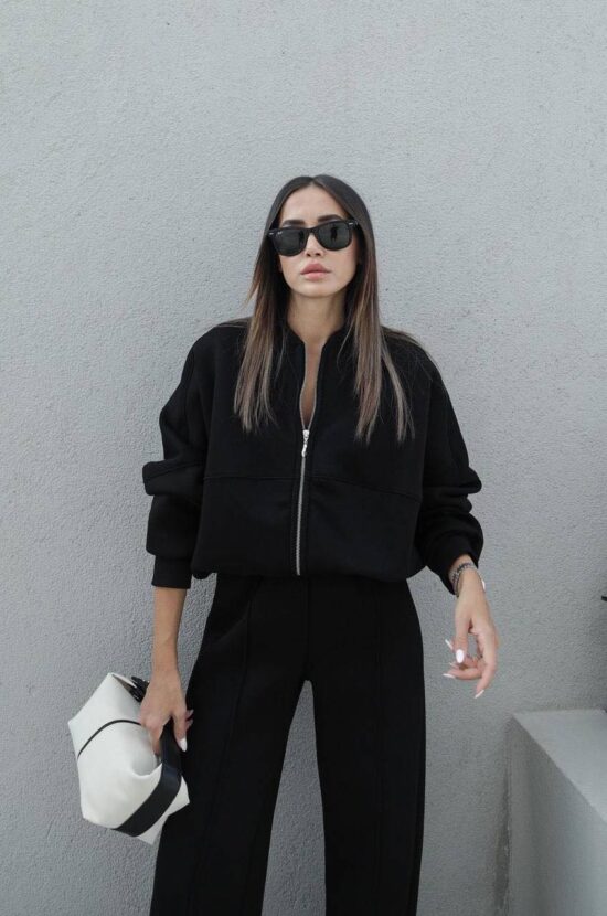 A woman wearing the Zae Casual set in black, featuring a black jacket and wide leg pants.